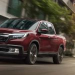 A red 2020 Honda Ridgeline RTL-E is driving down a city street.