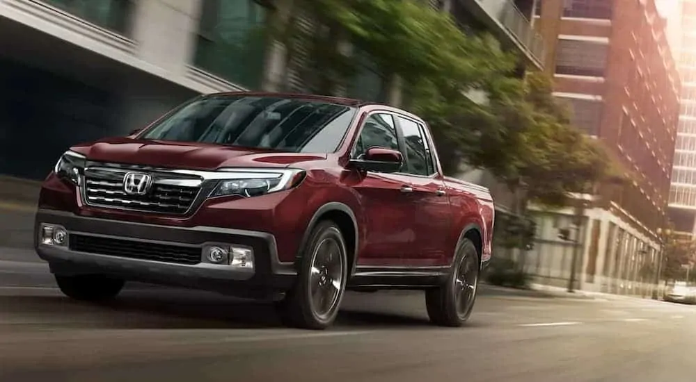 A red 2020 Honda Ridgeline RTL-E is driving down a city street.