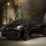 A black 2020 Toyota Sienna is parked in front of a wall covered in ivy.