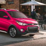 A red 2021 Chevy Spark is parked outside a cafe.