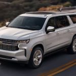 A white 2021 Chevy Suburban Premier driving down the road after winning the 2021 Chevy Suburban vs 2021 Chevy Tahoe comparison.