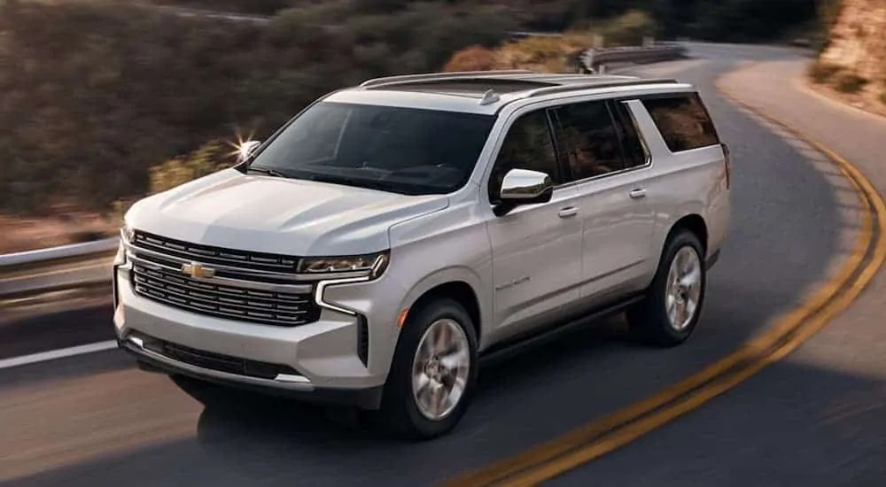 A white 2021 Chevy Suburban Premier driving down the road after winning the 2021 Chevy Suburban vs 2021 Chevy Tahoe comparison.