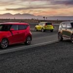 A red, a bright green, and a dark green 2021 Kia Soul are parked on a desert road.