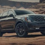 A black 2021 Kia Telluride is parked on dirt surrounded by rock formations after winning the 2021 Kia Telluride vs 2021 Honda Pilot comparison.
