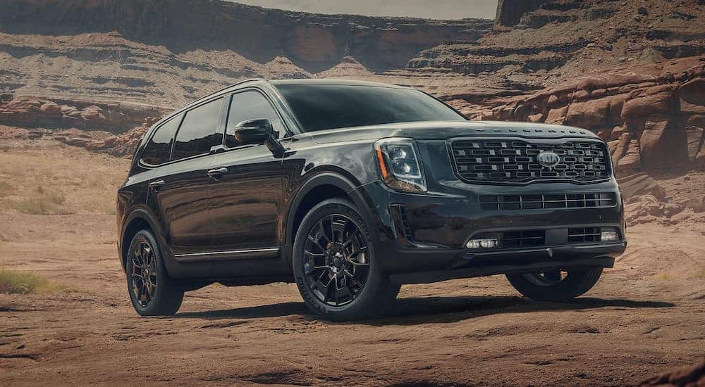 A black 2021 Kia Telluride is parked on dirt surrounded by rock formations after winning the 2021 Kia Telluride vs 2021 Honda Pilot comparison.