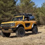 A yellow 2021 Ford Bronco 2-door is driving on a dirt trail.