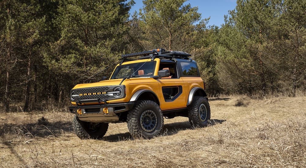 A yellow 2021 Ford Bronco 2-door is driving on a dirt trail.