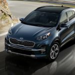 A blue 2020 Kia Sportage is driving around a sharp corner after leaving a Kia dealer near me.