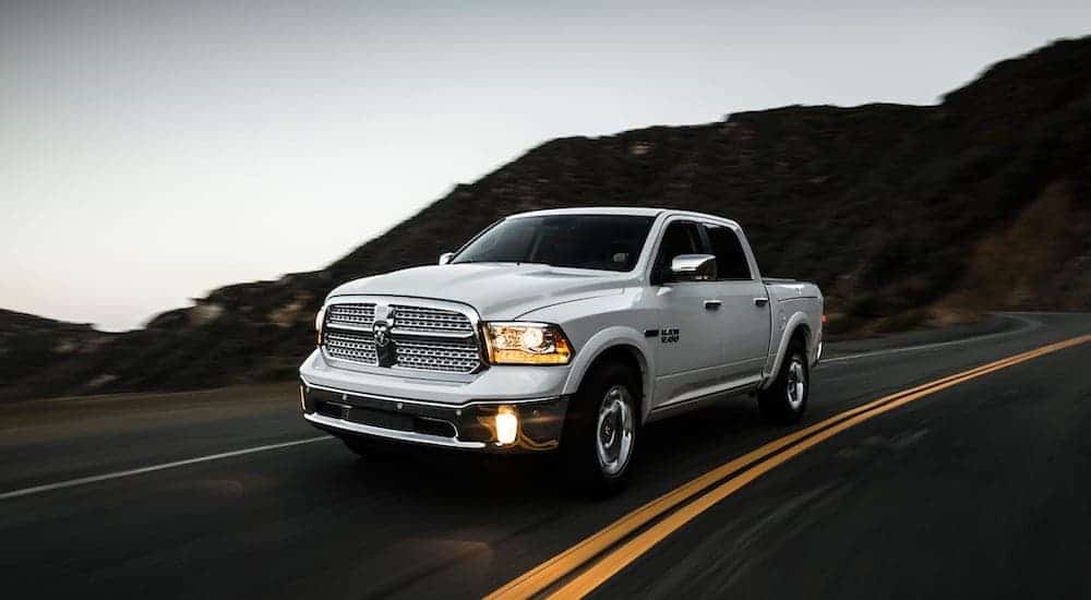 A silver 2015 used Ram 1500 is driving down the road.