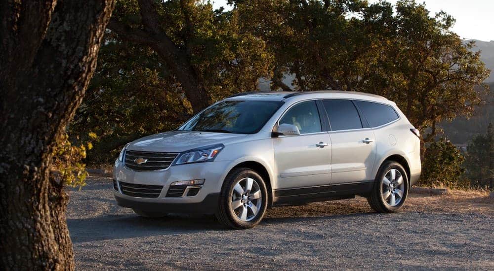 A silver 2016 Chevy Traverse LTZ is parked with a tree in forground.