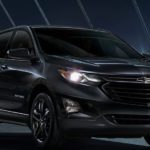 A black 2020 Chevy Equinox is parked in the city at night.