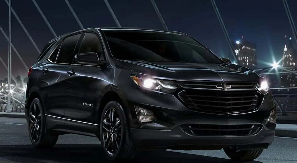 A black 2020 Chevy Equinox is parked in the city at night.