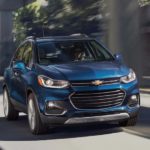 A blue 2021 Chevy Trax is driving under a bridge.