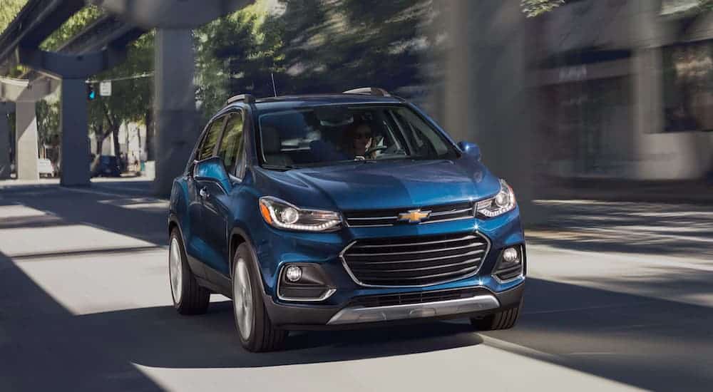 A blue 2021 Chevy Trax is driving under a bridge.