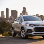 A silver 2021 Chevy Trax is parked on a hill with a city in the background.