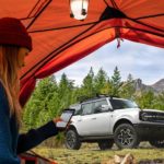 A silver 2021 Ford Bronco (4dr) Outer Banks is parked outside of a tent after being in the 2021 Ford Bronco (4dr) vs 2020 Jeep Wrangler Unlimited comparison.