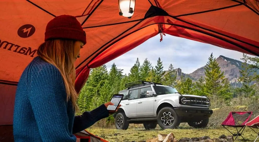 A silver 2021 Ford Bronco (4dr) Outer Banks is parked outside of a tent after being in the 2021 Ford Bronco (4dr) vs 2020 Jeep Wrangler Unlimited comparison.