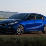 A blue 2021 Kia Forte GT is parked in a field angled left.