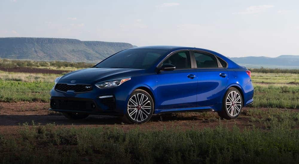 A blue 2021 Kia Forte GT is parked in a field angled left.