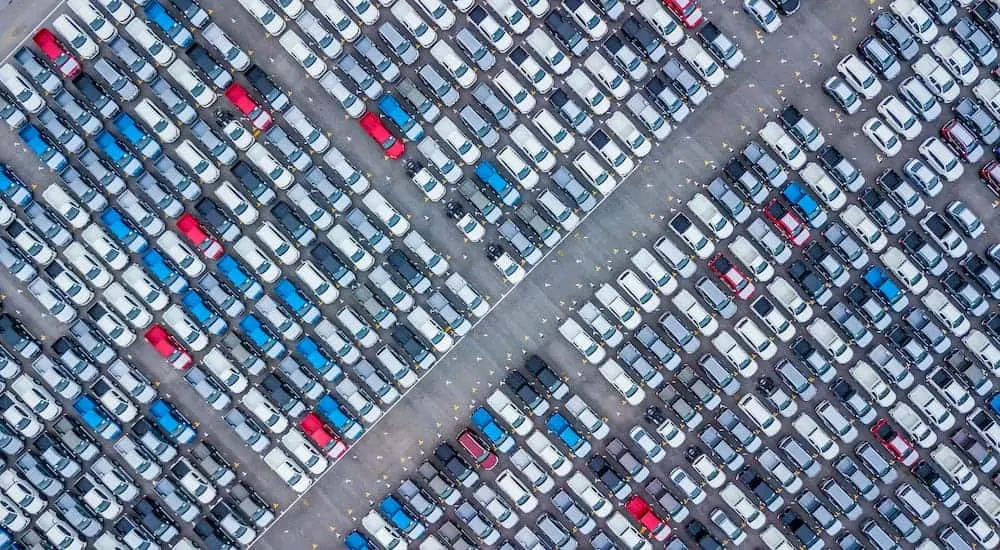 A birds eye view is showing a dealership parking lot full of automobiles.