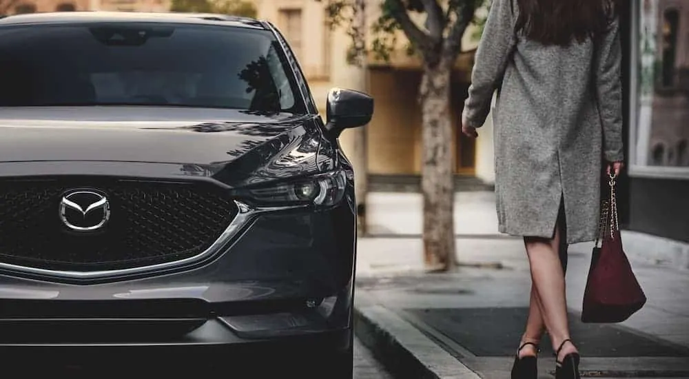 A grey 2021 Mazda CX-5 is parked on a city street after leaving a Mazda dealer near you.