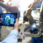 A man with a tablet is monitoring frame welding automation.