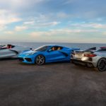 A white, a blue, and a silver 2021 Chevy Corvette are parked in front of the ocean.