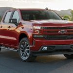 A red 2021 Chevy Silverado 1500 is parked in front of a farm after winning the 2021 Chevy Silverado 1500 Diesel vs 2021 Ram 1500 Diesel comparison.