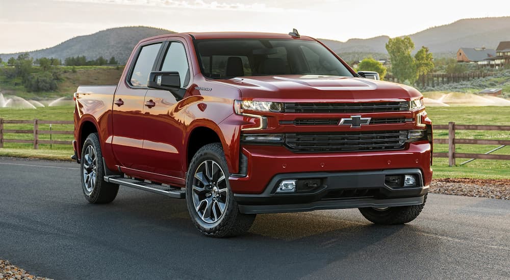 A red 2021 Chevy Silverado 1500 is parked in front of a farm after winning the 2021 Chevy Silverado 1500 Diesel vs 2021 Ram 1500 Diesel comparison.