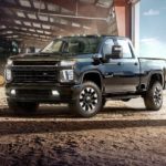 A black 2021 Chevy Silverado 2500 Carhartt Edition is parked in the open garage door of a tractor storage building.