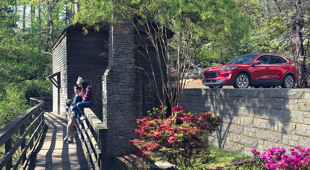 A red 2021 Ford Escape Titanium is shown from the side with a couple on a bridge nearby.