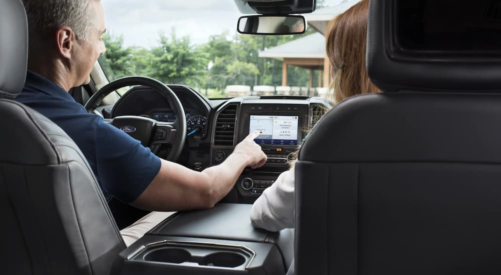 A couple in a 2020 Ford Expedition are using the touch screen.