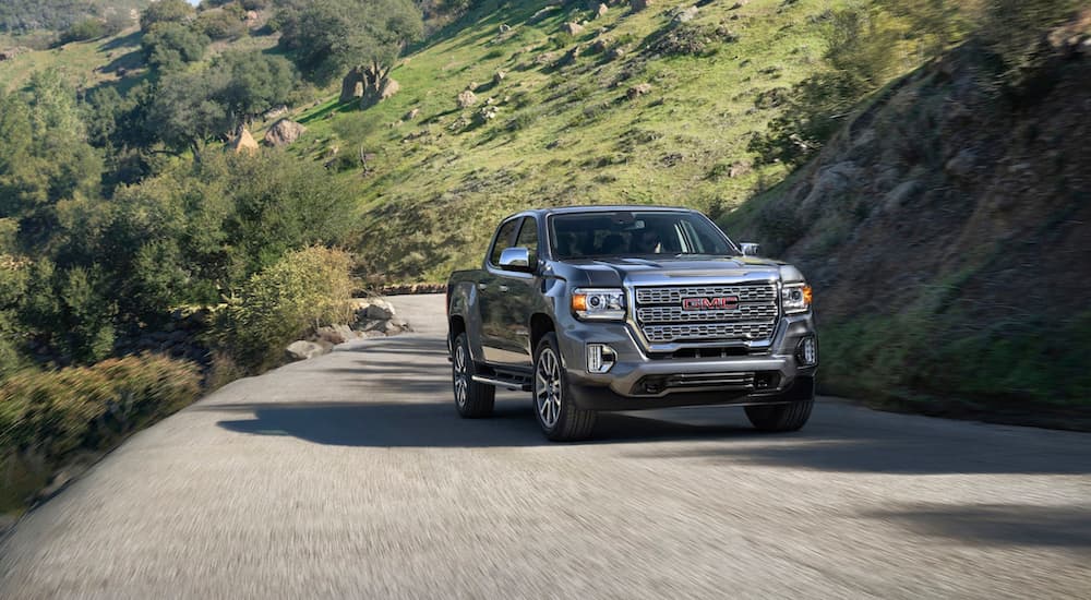 A grey 2021 GMC Canyon is driving on a winding mountain road.