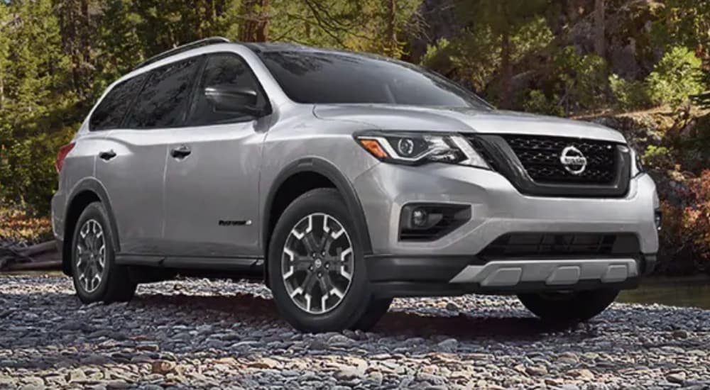 A silver 2020 Nissan Pathfinder is parked on a rocky river shore.