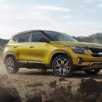 A yellow 2021 Kia Seltos is parked on dirt in front of mountains after winning the 2021 Kia Seltos vs 2021 Nissan Rogue comparison.