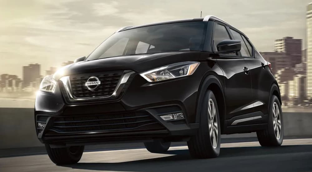 A black 2020 Nissan Kicks is driving away from a city.