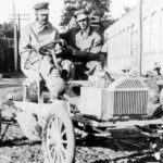 A 1904 Buick Model B Touring is shown in black and white parked in lumber yard.