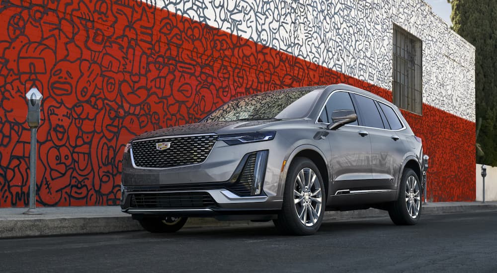 A grey 2021 Cadillac XT6 is parked on a side street in front of a red and white building after leaving a Cadillac dealer.