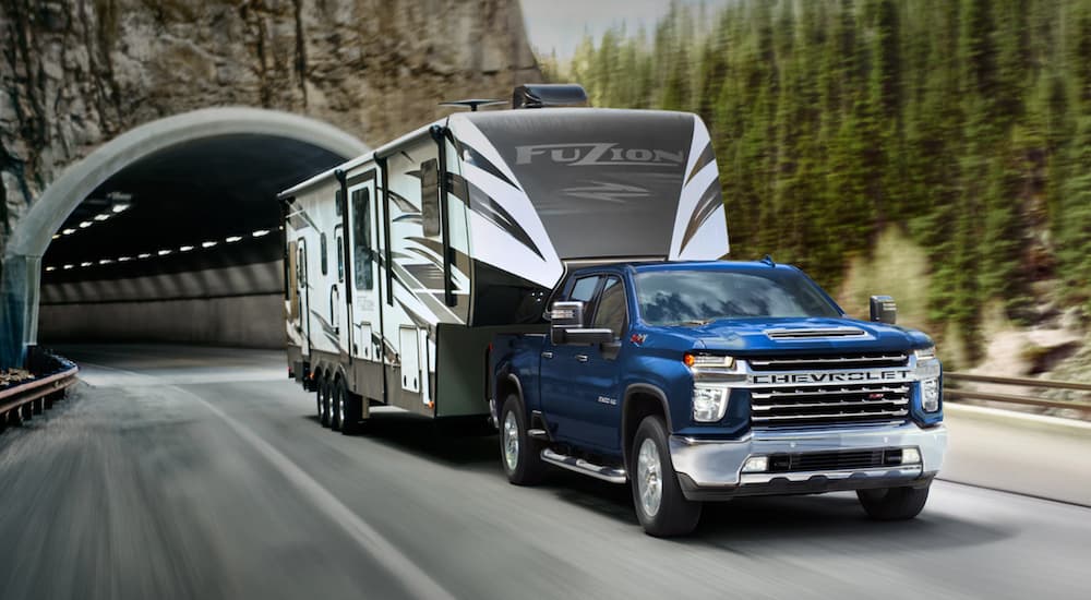 A dark blue 2021 Chevy Silverado 2500 HD is towing a camper out of a tunnel.