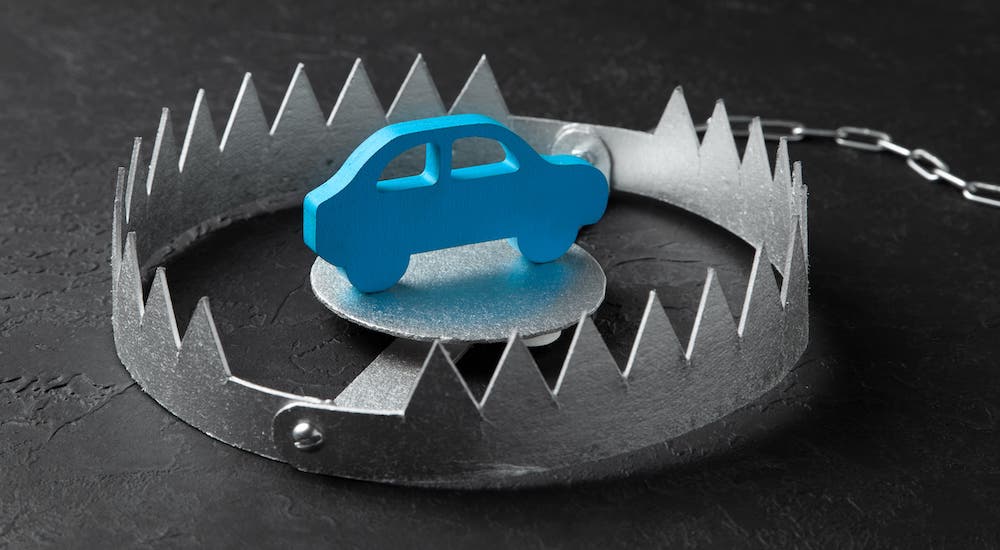 In current auto news, predatory lending, depicted here as a blue toy car in a bear trap.