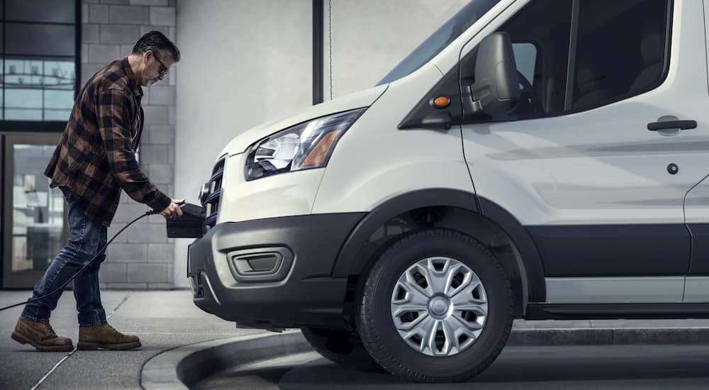 A man is charging a white 2022 Ford E-Transit.