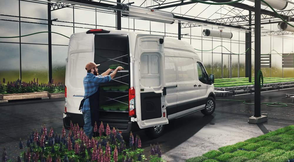 A man is loading flowers into a white 2022 Ford E-Transit at a nursery.