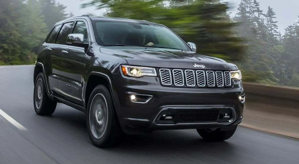 A popular Jeep model, a black 2020 Jeep Grand Cherokee, is driving down a misty mountain road.