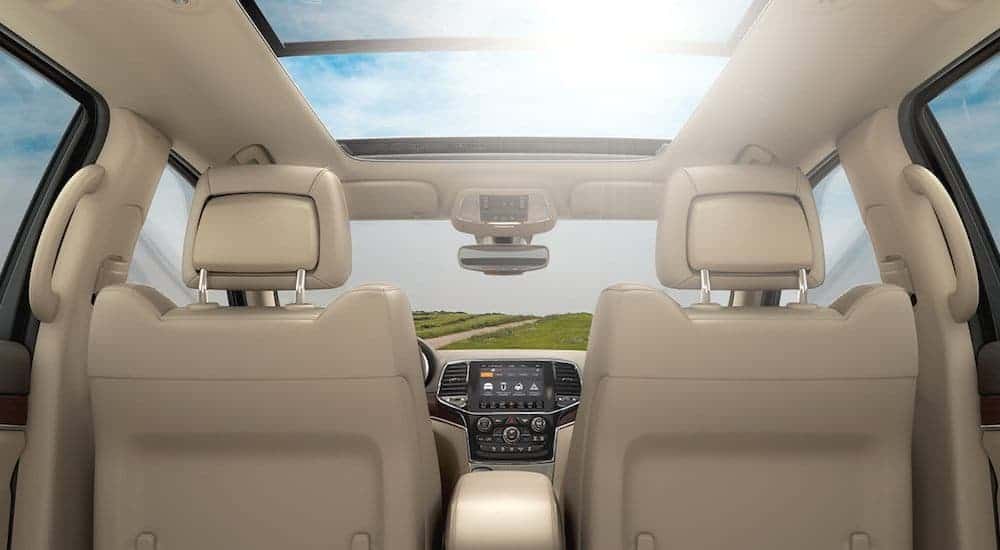 The tan interior and sunroof is shown from the back seat in a 2020 Jeep Grand Cherokee.