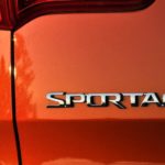 A close up of the badge on an orange 2022 Kia Sportage.