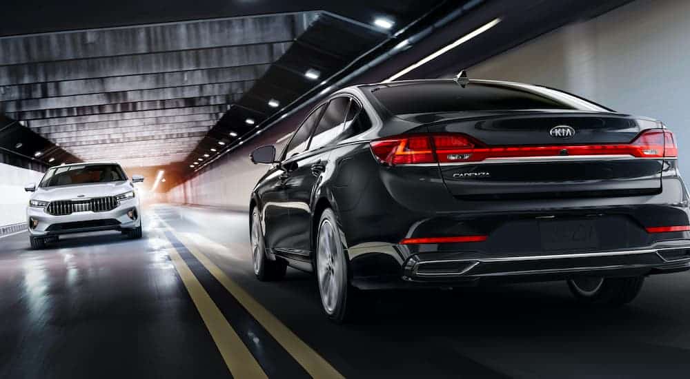 A black and a white 2021 Kia Cadenza are passing each other in a tunnel.