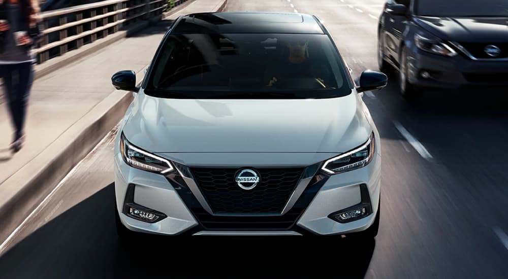 A white 2021 Nissan Sentra is shown from the front driving on a highway.