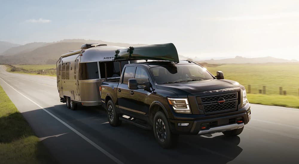 A black 2021 Nissan Titan is towing an Airstream with a canoe on the roof.