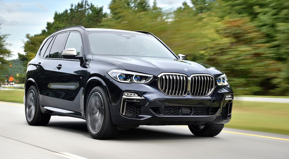 A black 2018 Used BMW X5 is driving on a highway past trees.