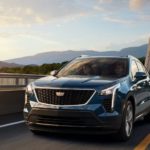 A blue 2019 used Cadillac XT4 is driving over a bridge.